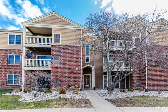 Front view of a multi-story residential building with brick and wooden exterior and balconies.