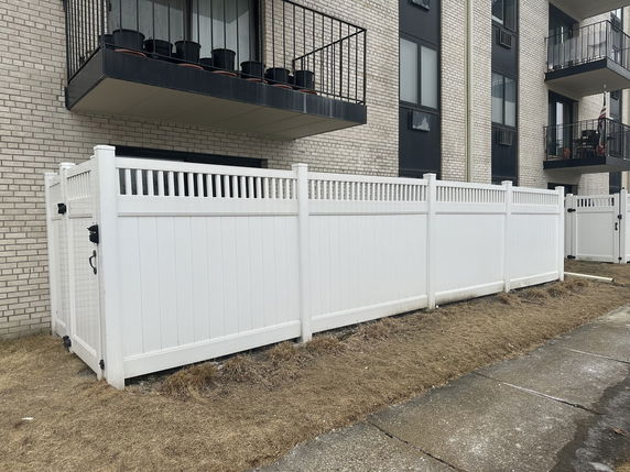 Front view of a building with a white fence and balconies.