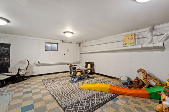 Indoor play area with toys and a slide in a basement room.