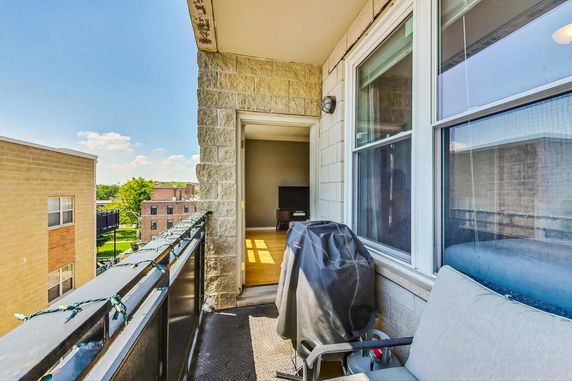 Balcony view looking out over adjacent buildings and greenery.