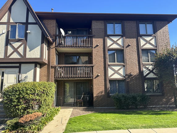 Front view of a three-story residential building with brick and Tudor-style elements.