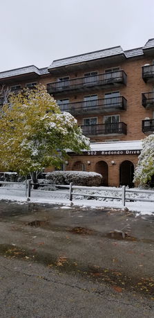 Front view of a multi-story building with balconies, during snowy weather.