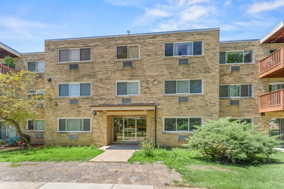 Front view of a three-story brick apartment building with multiple windows.
