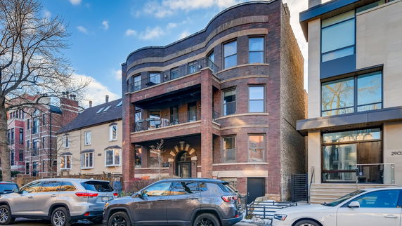 Front view of a multi-story brick residential building with balconies.