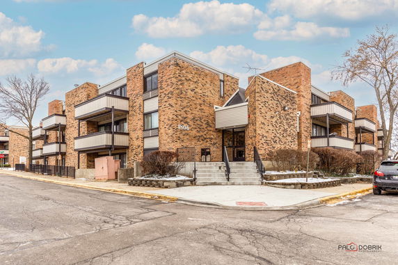 Front view of a multi-story apartment building with brick exterior and balconies.