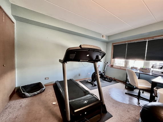 Interior room with gym equipment including a treadmill and exercise bike.