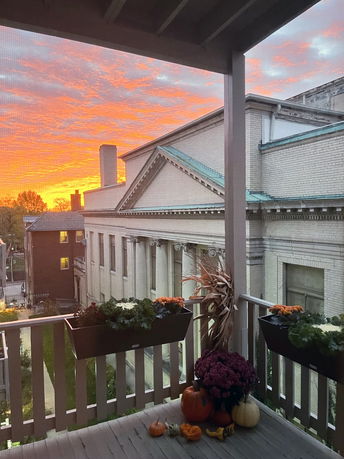 View of surrounding area with a large building and vibrant sunset seen from a balcony.