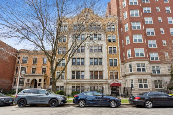 Front view of a multi-story residential building with ornate facade and large windows.