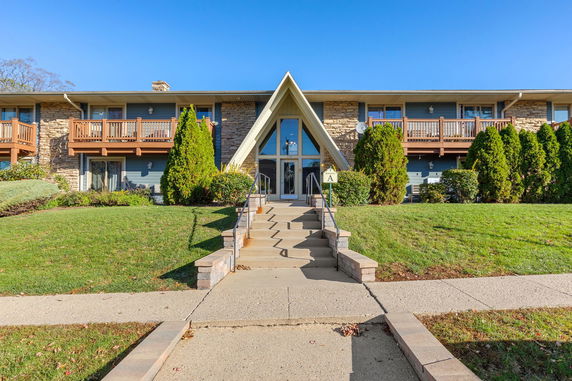Front view of a two-story building with a central A-frame entrance and stone facade.