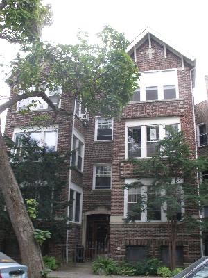 Front view of a multi-story brick building with trees in front.