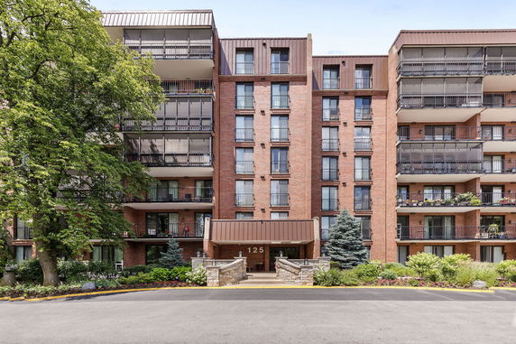 Front view of a multi-story brick apartment building with balconies.