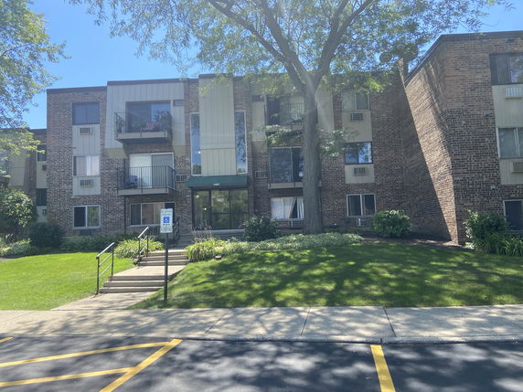 Front view of a multi-story brick apartment building with balconies.