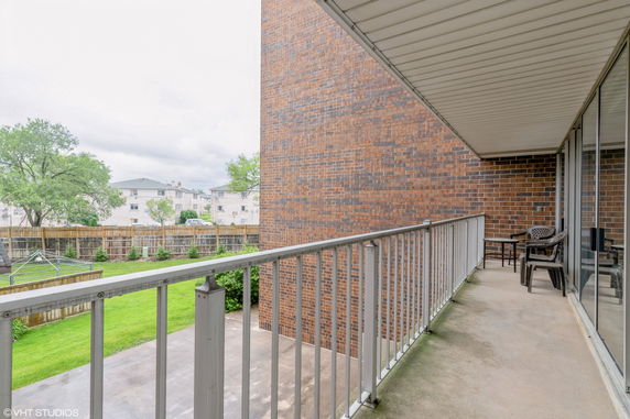 Balcony view showing neighboring buildings and a grassy area.