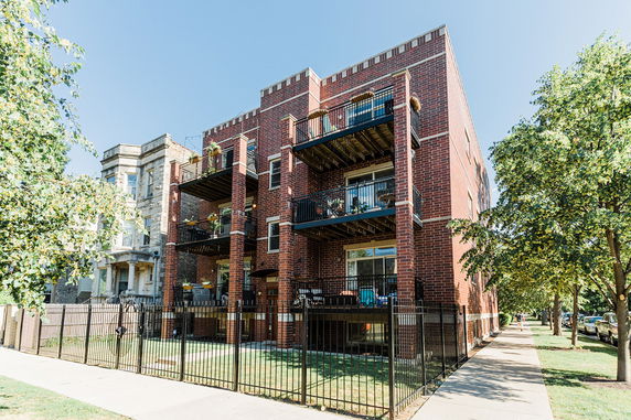 Front view of a three-story brick apartment building with balconies.