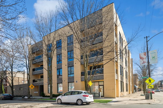 Front view of a multi-story apartment building with large windows.