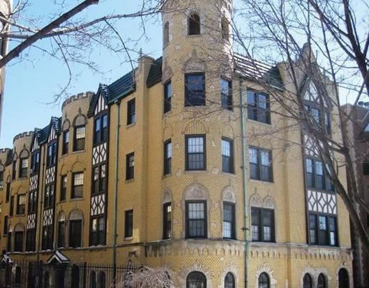 Front view of a multi-story building with unique architectural design and yellow brick exterior.