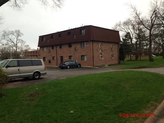 Front view of a multi-story brick apartment building with a sloped roof.