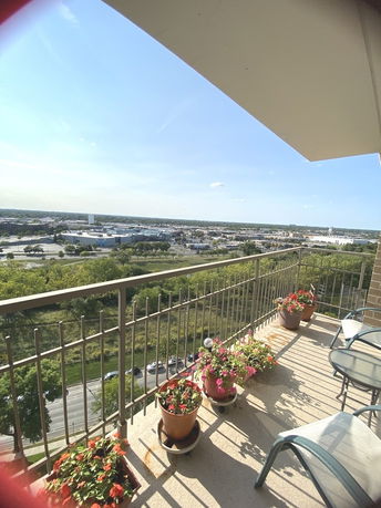 Balcony with potted plants overlooking a wide view of surrounding cityscape.