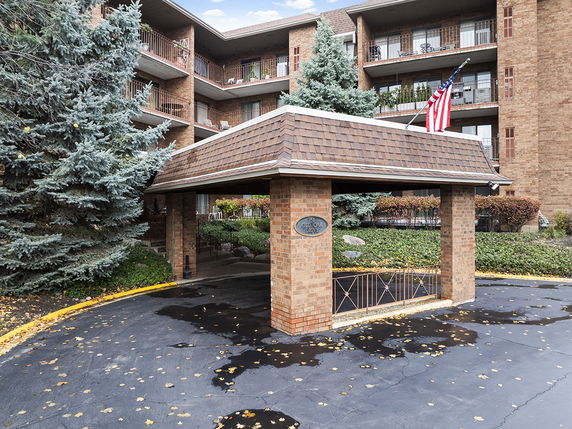 Front view of a multi-story brick apartment building with balconies and a covered entrance.