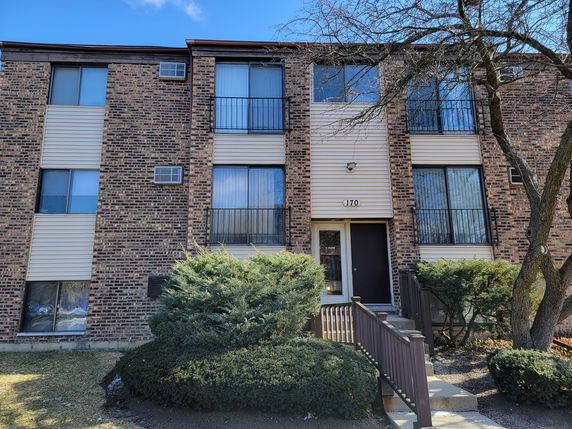 Front view of a three-story brick apartment building with large windows.