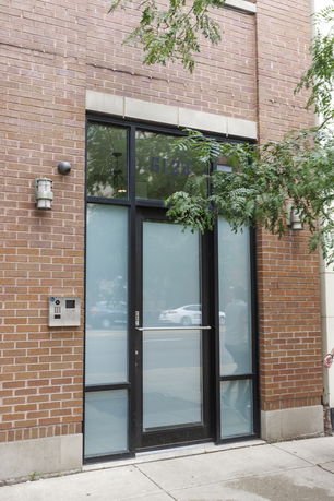 Front view of an entrance with large glass door and brick exterior.