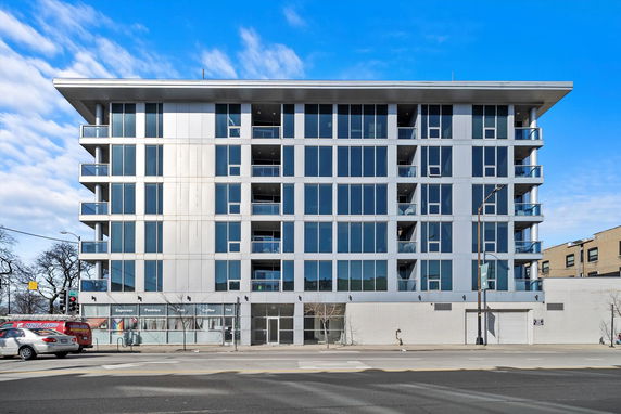 Front view of a modern multi-story building with large glass windows.