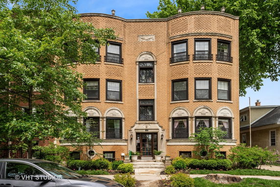 Front view of a three-story brick building with symmetrical design and decorative elements around windows.