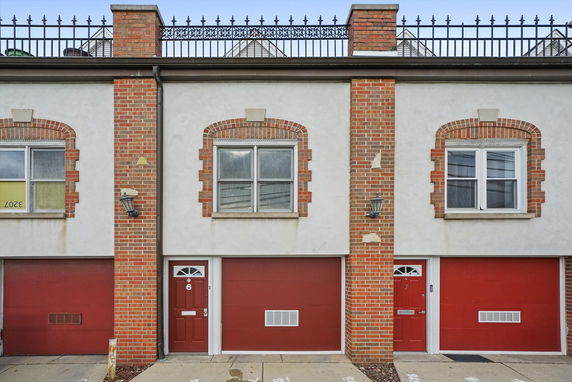 Front view of a multi-story building with brick facade and garage doors.