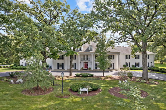 Front view of a large multi-story house with white exterior and red front door.