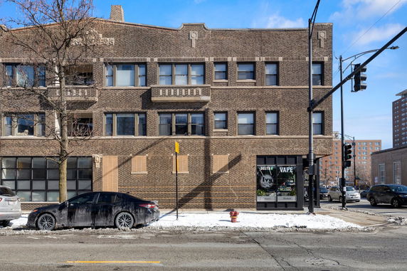 Front view of a multi-story brick building with large windows.