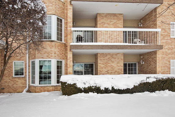 Front view of a brick building with balconies and snow-covered ground.