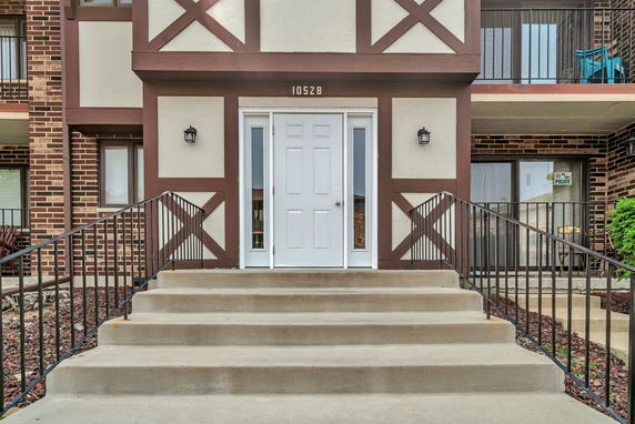 Front view of a building entrance with stairs and railings.