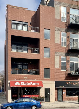 Front view of a multi-story brick building with a ground-floor commercial space.