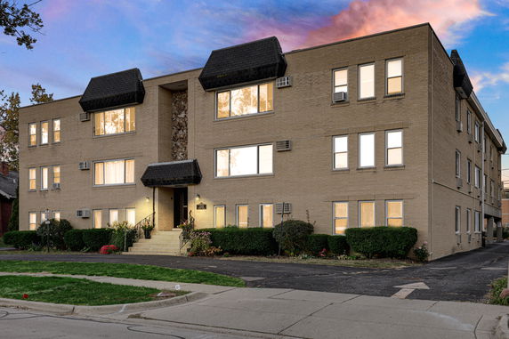 Front view of a three-story apartment building with multiple windows and entry steps.