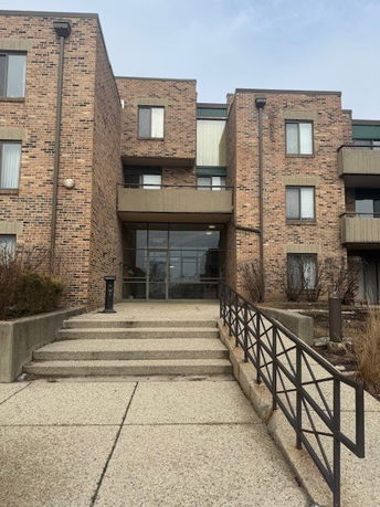 Front view of a multi-story brick building with a staircase leading to the entrance.