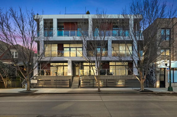 Front view of a three-story modern apartment building with balconies.
