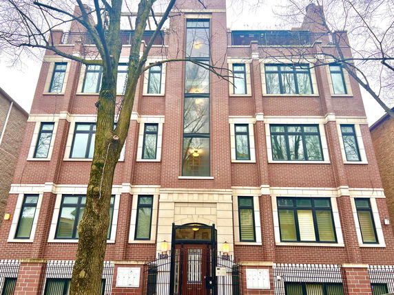 Front view of a three-story brick building with large windows and a central entrance.