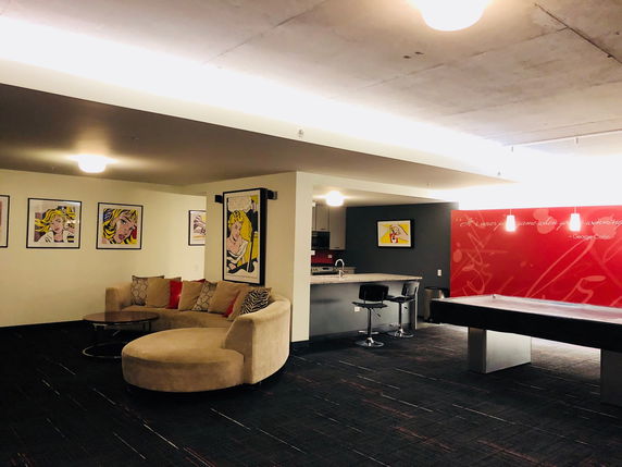 Interior of a recreation area with a seating arrangement, kitchenette, and a game table.