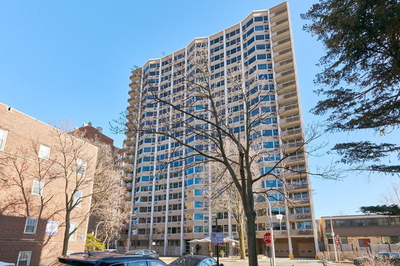 Front view of a tall residential building with multiple floors and balconies.