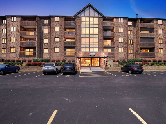 Front view of a multi-story brick apartment building with balconies