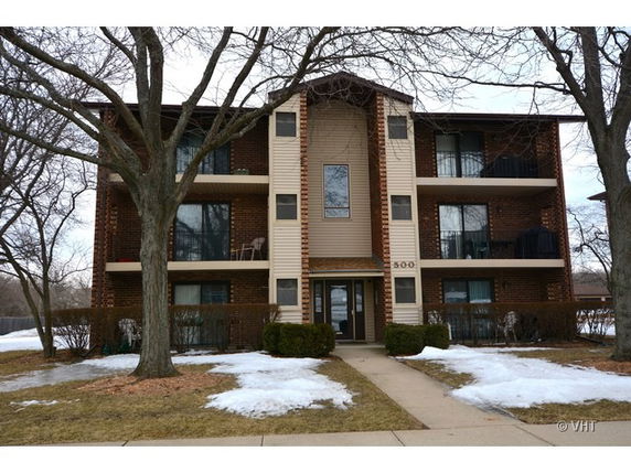 Front view of a three-story apartment building with balconies.