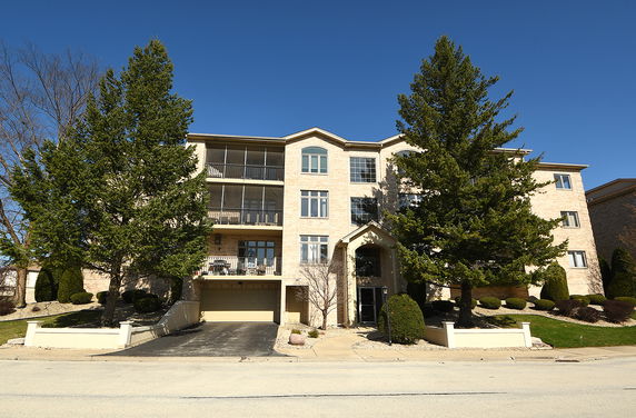 Front view of a four-story residential building with brick facade and balconies.