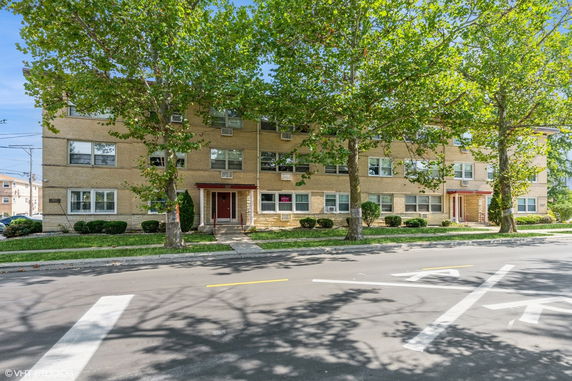 Front view of a three-story brick apartment building with multiple entrances.
