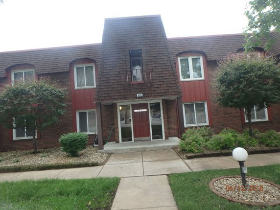 Front view of a two-story building with a unique roof and front entrance walkway.