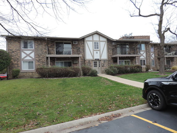 Front view of a two-story apartment building with brick exterior and multiple balconies.