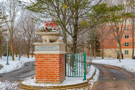 Entrance of a condominium complex with a stone monument and gate.