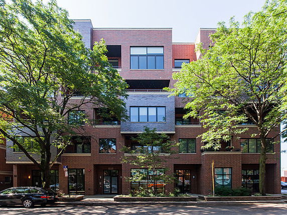 Front view of a multi-story brick building with trees in front.