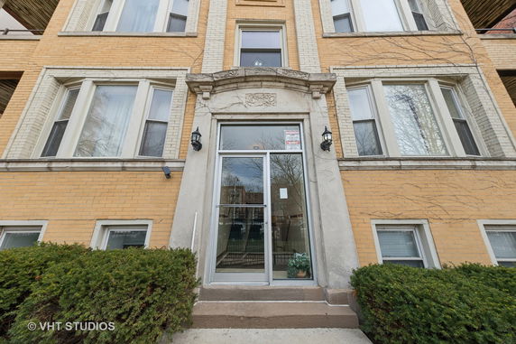 Front view of a multi-story brick building entrance with large windows and glass door.