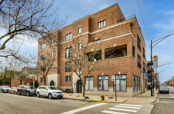 Front view of a multi-story brick building with large windows.