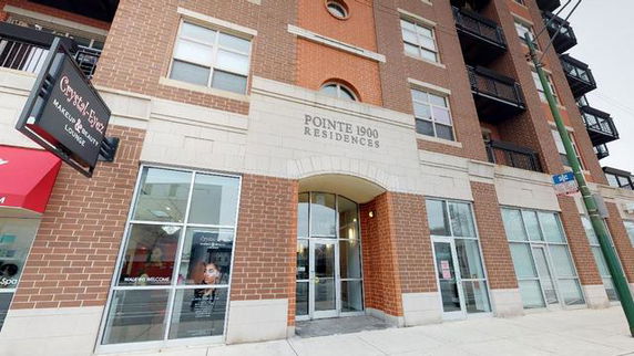 Front view of a multi-story residential building with brick facade and glass doors.